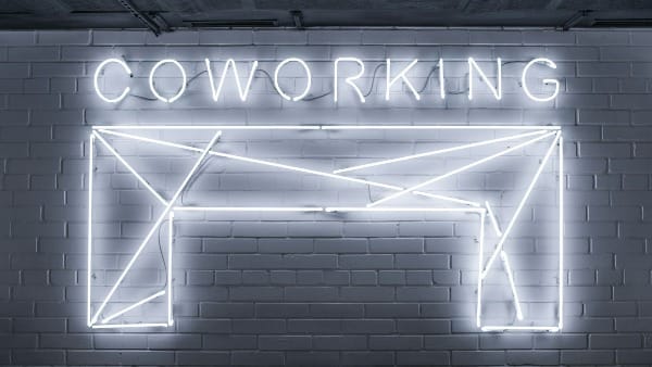 Foto mostra parede com escrito Coworking em neon.